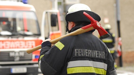 Feuerwehrmann trägt eine Axt auf der Schulter © imago / Seeliger 