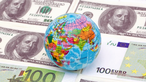 Ein Globus liegt auf Dollar- und Euroscheinen (Symbolbild). © picture alliance / PPE | PPE 