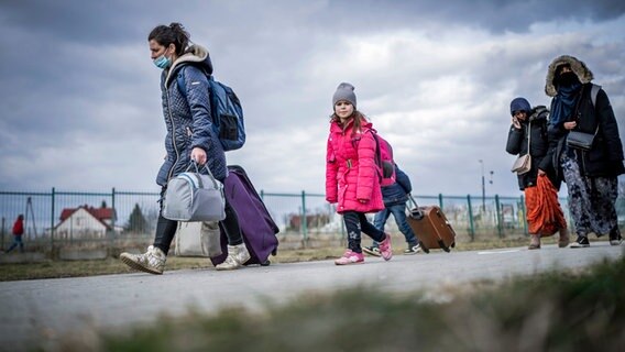 Geflüchtete aus der Ukraine gehen nach ihrem Grenzübertritt in Polen durch das polnische Grenzgebiet. © dpa Foto: Michael Kappeler