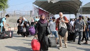 Mehrere Menschen mit Koffern und Reisetaschen in den Händen stehen am Grenzübergang Rafah vom Gazastreifen nach Ägypten. © dpa bildfunk/XinHua Foto: Khaled Oma