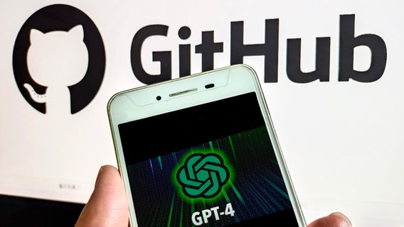 Ein Handy mit GPT-4-Logo auf dem Display, dahinter das Logo von GitHub (Themenbild) © picture alliance Foto: CFOTO