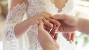 Ein Bräutigam steckt seiner Braut den Ehering an den Ringfinger. © Colourbox Foto: Artem Zakharov