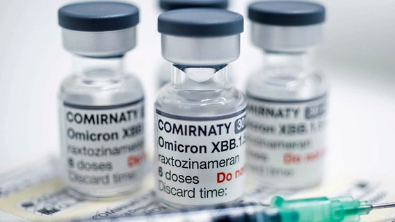 Gläschen mit jeweils sechs Dosen des neuen angepassten Corona-Impfstoffs von Biontech/Pfizer stehen auf einem Tisch in einer Apotheke. (Foto vom 18.9.2023) © Christophe Gateau/dpa 