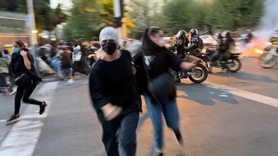 Frauen fliehen vor der Polizei während eines Protestes in der Innenstadt von Teheran, Iran. © Uncredited/AP/dpa 