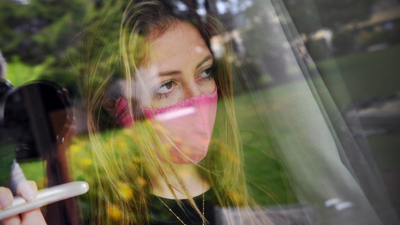 Ein Frau steht mit einer Atemmaske an einem Fenster. © picture alliance / SvenSimon | Frank Hoermann/SVEN SIMON Foto: Frank Hoermann/Sven Simon