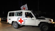 Ein Fahrzeug des Roten Kreuzes fährt im Dunklen im Gazastreifen auf einer Straße Richtung Grenzübergang nach Ägypten. © dpa-Bildfunk/AP Foto: Xin Hua