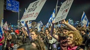 In einer Menschenmenge werden bei einer Demonstration in Jerusalem in Israel Plakate mit regierungskritischem Inhalt hochgehalten. © dpa-Bildfunk Foto: Ilia Yefimovich