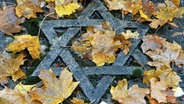 Auf einem jüdischen Friedhof  liegt feuchtes Herbstlaub auf einem Grab mit dem Davidstern. © picture alliance / dpa Foto: Martin Schutt