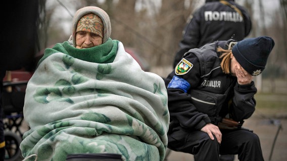 Eine ukrainische Polizistin ist von ihren Gefühlen überwältigt, nachdem sie Menschen getröstet hat, die aus der Kiewer Vorstadt Irpin evakuiert wurden. © dpa-Bildfunk 