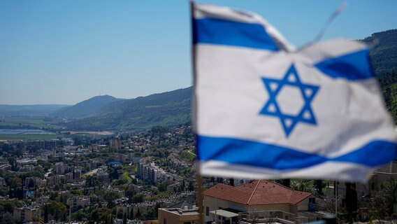 Blick auf die israelische Stadt Kiryat Shmona. Im Vordergrund weht die israelische Flagge. © picture alliance / AP Foto: Ariel Schalit
