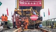 Chinesische Eisenbahnarbeiter bei Schienenarbeiten an einer Strecke in Laos. © picture alliance Foto: Xinhua News Agency