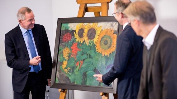 NDR Intendant Lutz Marmor und zwei Mitarbeiter betrachten das Gemälde "Sonnenblumen" von Emil Nolde © dpa - Bildfunk Foto: Christian Charisius