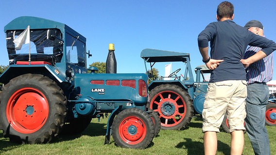 Zwei Besucher betrachten einen alten Traktor Lanz auf dem Ausstellungsgelände der Norla in Rendsburg © NDR Foto: Robert Holm