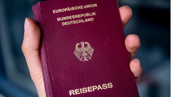 Ein Deutscher Reisepass in der Hand einer Frau. © dpa Foto: Fabian Sommer