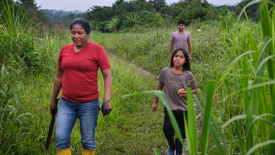 Eine Frau mit Machete und zwei Kinder laufen im Regenwaldgebiet Ecuadors. © NDR / Zeitenspiegel / Jelca Kollatsch Foto: Jelca Kollatsch