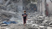 Palästinensische Gebiete, Flüchtlingslager Bureij: Ein palästinensisches Kind steht nach den israelischen Luftangriffen auf Überresten zerstörter Gebäude. © picture alliance / ZUMAPRESS.com | Foto: Naaman Omar