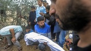Mitglieder einer Familie begraben die Leichen ihrer Angehörigen, die nach einem israelischen Bombenangriff im südlichen Gazastreifen getötet wurden. © dpa Foto: Mohammed Talatene