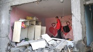Palästinenser betrachten die Zerstörungen durch die israelische Bombardierung des Gazastreifens. © picture alliance/dpa/AP Foto: Hatem Ali