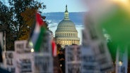 Das US-Kapitol ist zu sehen, während sich Demonstranten bei einer pro-palästinensischen Demonstration für eine Feuerpause im Gazastreifen versammeln. © AP/dpa Foto: Jose Luis Magana