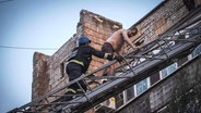 Ukrainische Rettungskräfte vom Katastrophenschutz retten Menschen aus einem beschädigten Gebäude nach Raketeneinschlägen. © AP Foto: Evgeniy Maloletka