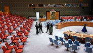 Menschen stehen in dem größtenteils leeren Saal des UN-Sicherheitsrats am Sitz der Vereinten Nationen in New York. © AP/dpa Foto: Seth Wenig