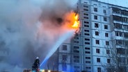Feuerwehrmänner löschen ein durch eine Rakete in Brand geratenes Wohnhaus. © picture alliance/dpa/National Police of Ukraine 