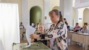 Eine Frau steckt einen Wahlzettel in eine Wahlurne. © picture alliance/dpa/TASS Foto: Erik Romanenko