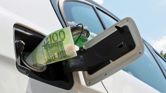 Ein 100-Euro-Geldschein steckt in einer Tankklappe am Auto. © fotolia.com Foto: babimu
