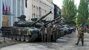 Milizionäre der Volksrepublik Luhansk stehen bei einer Ausstellung erbeuteter ukrainischer Panzer und Waffen in Lyssytschansk. © Uncredited/AP/dpa 