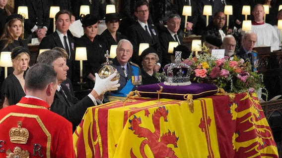 Der Reichsapfel und das Zepter werden bei der Beisetzung von Königin Elizabeth II. in der St. Georges Kapelle auf Schloss Windsor vom Sarg entfernt. © Jonathan Brady/PA Wire/dpa 