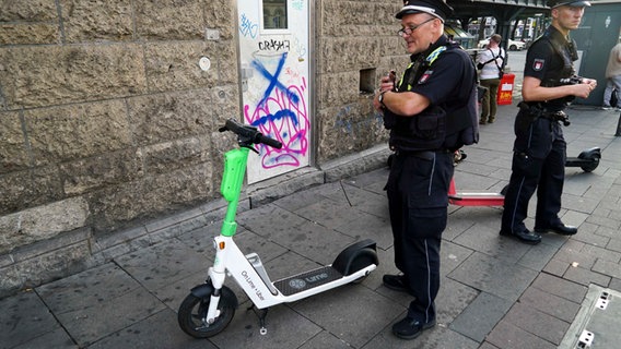 Polizist schreibt am Hamburger Hauptbahnhof Strafzettel für verkehrsgefährdend abgestellte E-Scooter © picture alliance /ABB 