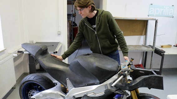 Der Student Finn Rutha steht an einem Motorrad, an dem er viele Metallteile durch Carbon ersetzt hat.  Foto: Claudio Campagna