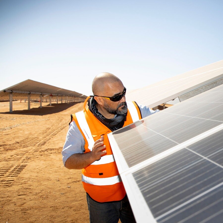 Ein Mitarbeiter schaut auf ein Solarpanel in einem Solarpark in der ägyptischen Wüsre Aswan. © picture alliance Foto: Ute Grabowski