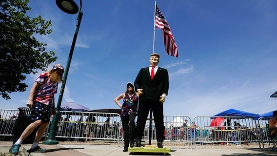 An einer Trump-Figur posiert eine Anhängerin unter der Flagge der USA © picture alliance Foto: Ross D. Franklin