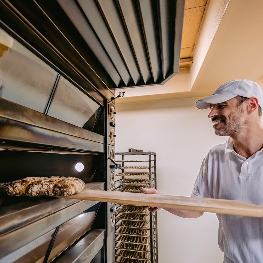 Ein Bäcker in Südtirol holt frisch gebackenes Brot aus dem Ofen © NDR Foto: Alexander Tempel