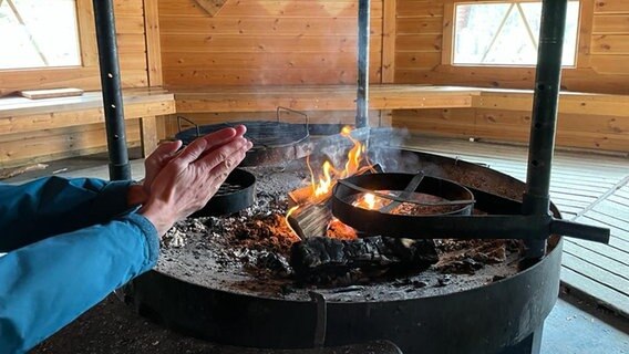 Jemand hält die Hände in die Nähe einer Feuerstelle © NDR Foto: Petra Martin