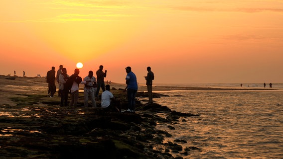 Menschen am Meer im Sonnenuntergang an der Küste von Somaliland in Afrika © NDR / Florian Guckelsberger Foto: Florian Guckelsberger
