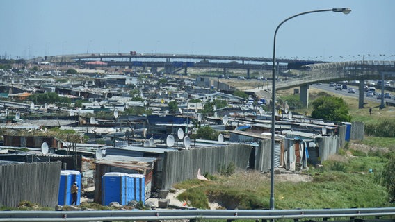 Wellblechdächer, soweit das Auge bis zur Autobahnbrücke reicht: Townships im Viertel Kayelitsha in Südafrika © NDR Foto: Ulrike Keding
