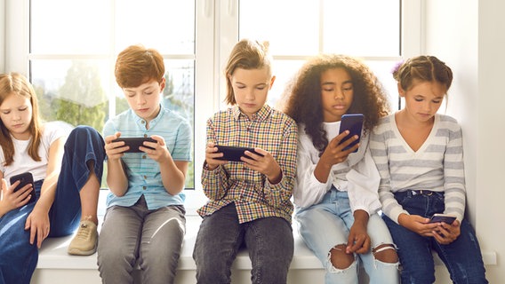 Eine Kindergruppe sitzt auf einer Fensterbank und jeder schaut auf sein Smartphone. © Colourbox Foto: #266241