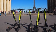 E-Tretroller zum Mieten stehen auf der Place du Trocadero, im Hintergrund ist der Eiffelturm zu sehen. © Christian Böhmer/dpa 