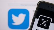 Der weiße Buchstabe X auf schwarzem Hintergrund auf einem Smartphone, im Hintergrund das bisherige Logo des Kurznachrichten-Dienstes Twitter © Monika Skolimowska/dpa 