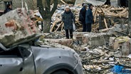 Menschen stehen in Slowjansk in der Ukraine vor den Trümmern von einem Gebäude. © dpa bildfunk/AP Foto: LIBKOS