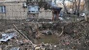 Ein Krater, der durch den Fall von Trümmern abgeschossener russischer Drohnen vor einem Wohnhaus in einem der Stadtteile von Odessa entstanden ist. © -/ukrin/dpa Foto: -/ukrin/dpa