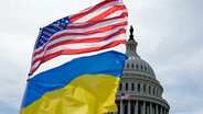 Die US-amerikanische und die ukrainische Flagge wehen vor dem Kapitol in Washington im Wind. © Mariam Zuhaib/AP/dpa 