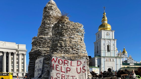 "Welt hilf uns!" steht auf einem verhüllten Denkmal vor dem Michaelskloster in Kiew. © ARD Foto: Andrea Beer