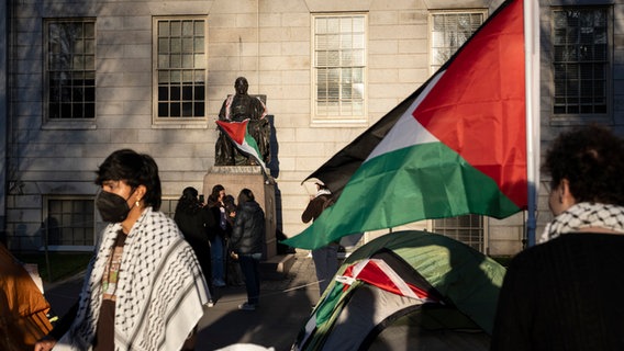 USA, Cambridge: Ein Student steht während eines Protestes gegen den Krieg in Gaza an der Harvard University vor der Statue von John Harvard. © Ben Curtis/AP/dpa 