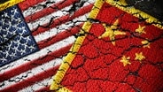 Die Fahnen von USA und China liegen übereinander, sie sind als Bruchstücke abgebildet. © dpa picture alliance/chromorange Foto: Christian Ohde
