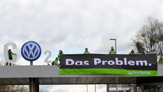Mehrere Greenpeace-Aktivisten stehen auf dem Eingang der VW-Zentrale in Wolfsburg und halten ein Banner mit der Aufschrift: "Das Problem" hoch. © dpa - Bildfunk Foto: Peter Steffen