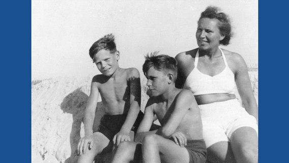Eine Frau und zwei Jungs in Badesachen sitzen an einem Strand (Schwarzweißbild) © Privatbesitz J. Gauck Foto: privat