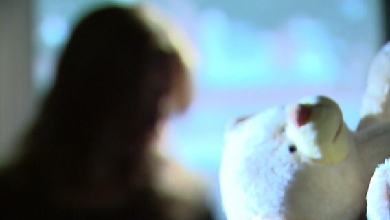 Im Vordergrund sieht man einen Teddybär, im Hintergrund die Silhuette eines Kindes. © ndr.de Foto: ndr.de
